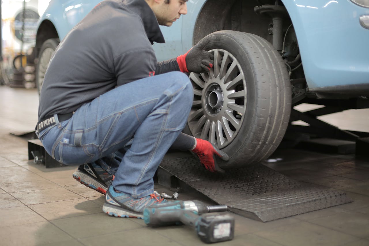 core-values Mechanic changing a car tire indoors, using tools for vehicle maintenance.